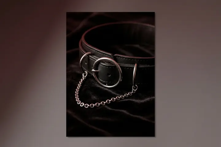 Collier de cuir noir et fine chaîne argentée posés sur un velours sombre, sous une lumière rasante